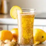 Glass of Natural Zepbound Drink with chia seeds, lemon, ginger, and turmeric on a white kitchen counter.